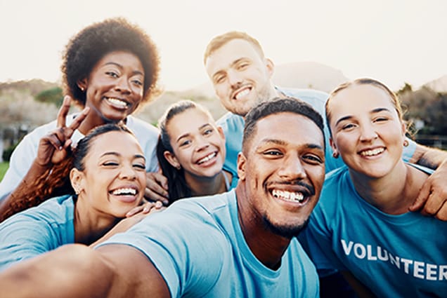 Diverse group of community volunteers smiling together in matching VOLUNTEER shirts